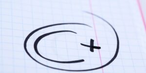 A school paper has "C+" written and circled in black marker.