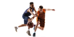 Two basketball players in action; one dribbles the ball while the other attempts to foul him.
