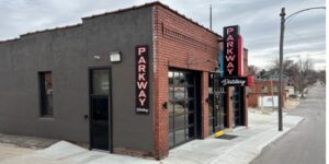 Outside view of Parkway Distillery, a brick building with red neon signs.
