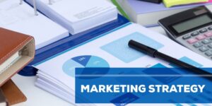Papers and graphs with a blue banner across them that says, "marketing strategy."