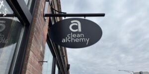 Minimalist style black sign on a brick building that says "clean alchemy."