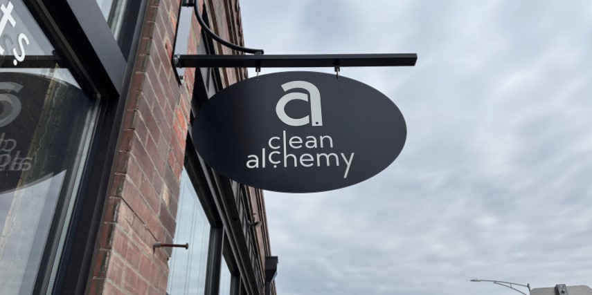 Minimalist style black sign on a brick building that says "clean alchemy."