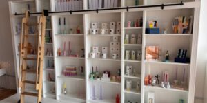 Clean white shelves display a variety of candles and melts in a shop.