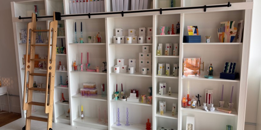 Clean white shelves display a variety of candles and melts in a shop. 