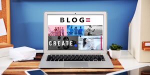 A laptop on a desk has images and text that says "Blog," and "Create" on the screen.