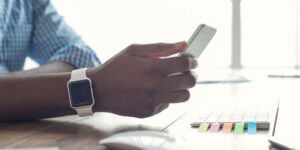 Close-up of a man's hand with a smartwatch holding a device.