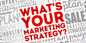 A background of a gray grid of marketing-related words and a red "What's Your Marketing Strategy?" stamped across it.