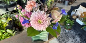 A flower arrangement shows pink and blue flowers with green leaf accents.