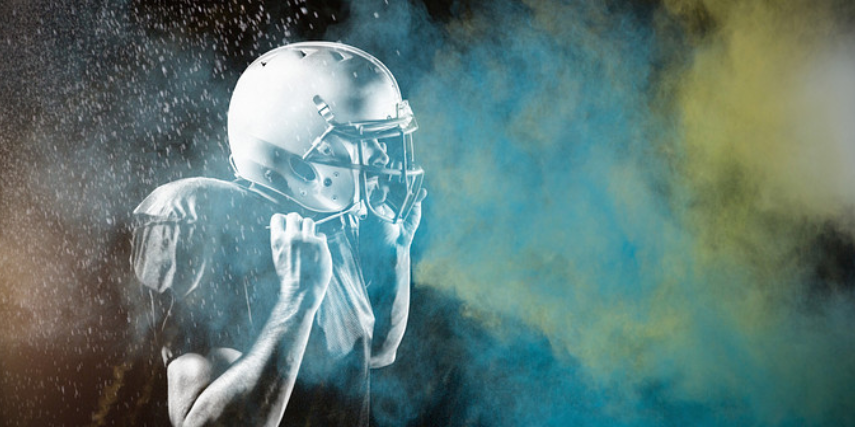 Hazy image of an arena football player holding onto his helmet.