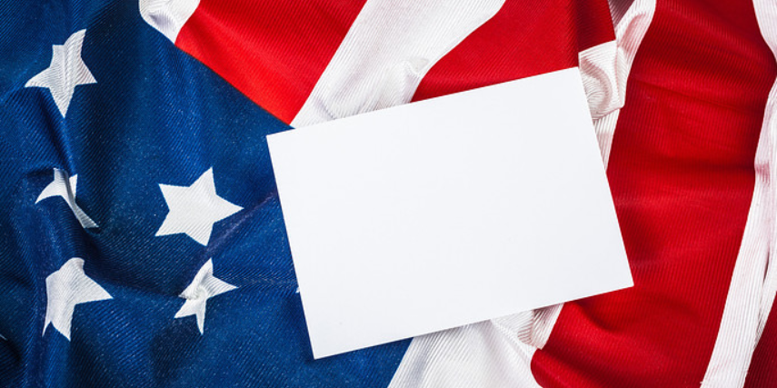 A plain, white envelope is laid on an American flag.