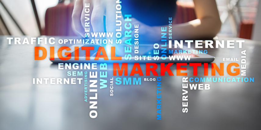 Marketing-related words float in front of someone sitting in front of a tablet with the words, "digital marketing" in red.