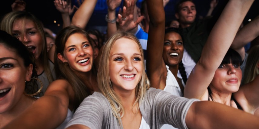 A young woman holds a phone taking a selfie with her friends.