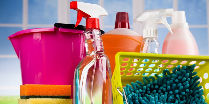 A colorful array of buckets, cleaners and sponges against a blue tile backdrop.