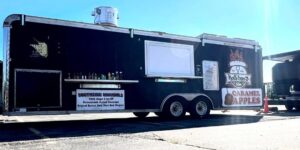 View from the side of a large food truck with the service window closed.