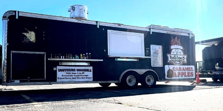 View from the side of a large food truck with the service window closed.