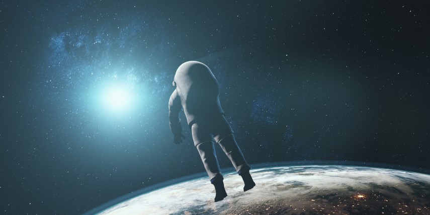 An astronaut in space floats above Earth with a bright light shining on him.
