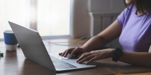 Close-up of a woman sitting at a table with her laptop in front of her.