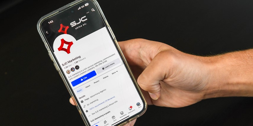A smartphone displaying a social media profile page for SJC Marketing.