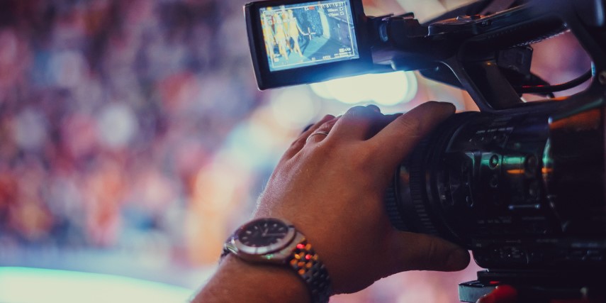 Close-up of a hand guiding a video camera at an event.