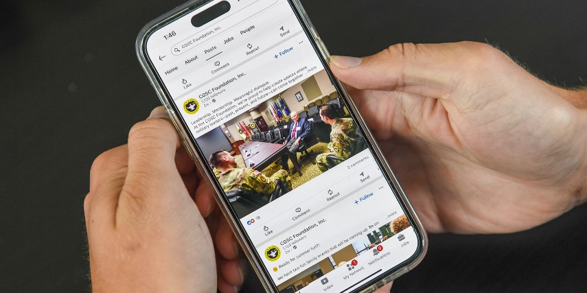 Close-up of two hands holding a smartphone with a LinkedIn feed showing on the screen.