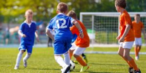 Youth soccer players in royal blue and red jerseys play a game on an outdoor field.
