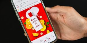 A smartphone shows a Facebook Ad for SJC Marketing, with lemons and a bottle of sunscreen against and red-and-white color palette.