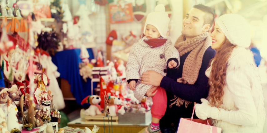 A young couple and their baby look at Christmas decor at a holiday fair.