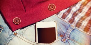 Jeans, a red and white flannel and a red cardigan with a mobile phone tucked into the pocket of the jeans.