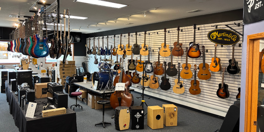 Rows of electric and acoustic guitars line the walls at Lanham Music, while box drums and equipment line the floor. 