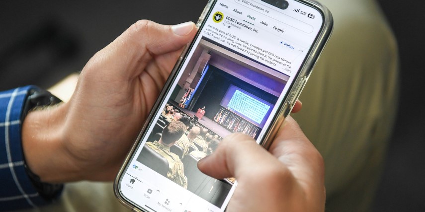 Closeup of a smartphone in someone's hands, with a social media platform on the screen.