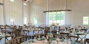 Inside of barn wedding venue is decorated with decor and table settings for a wedding.