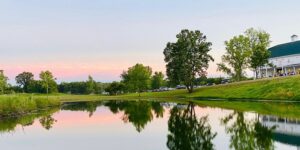 Outside of a wedding venue, the sun sets over a pretty pond.