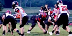 A group of high school students in full uniform participate in a football game.