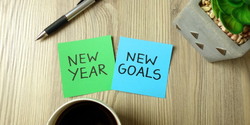 Blue and green Post-It notes on a desk that say "New Year" and "New Goals." 