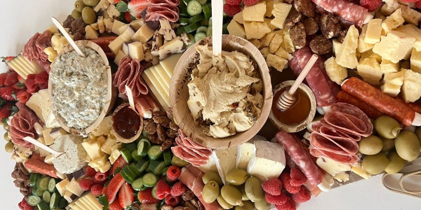 A charcuterie spread, including olives, cheese, sausage and dips.