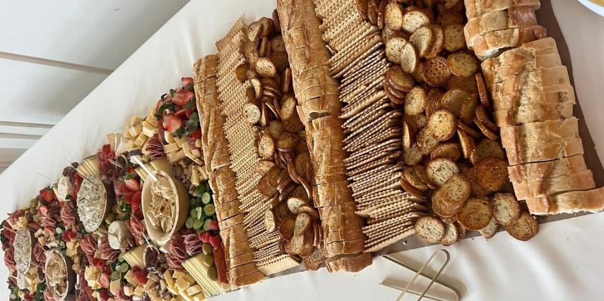A table is filled with bread, crackers and sausage in a spectacular charcuterie board.