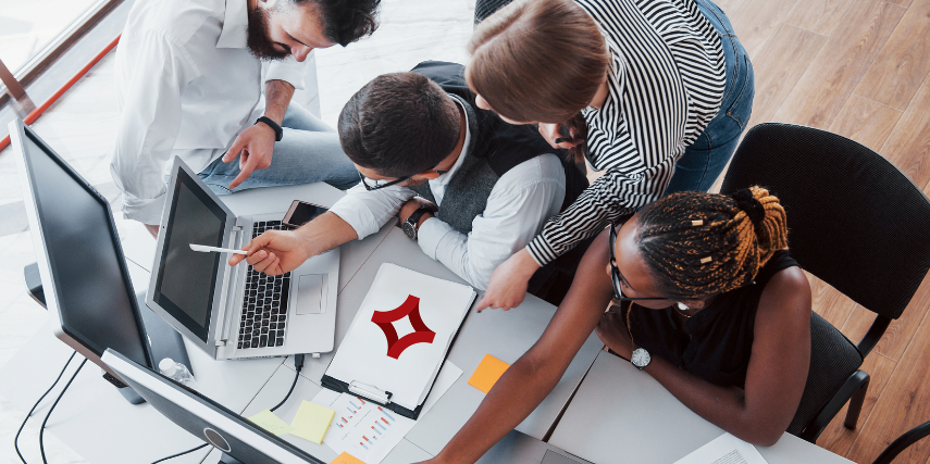 Overhead view of a group of professionals analyzing data on a computer monitor.