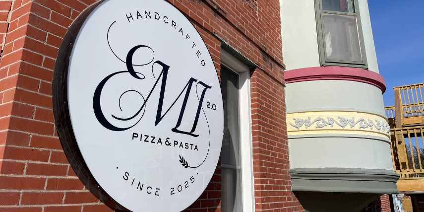 Outside view of EMI Ristorante, with an up-close look at the restaurant's sign against the brick wall.
