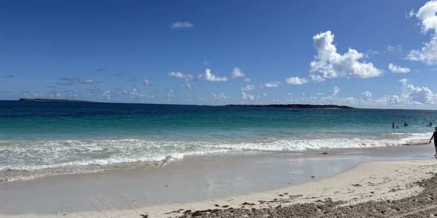 A beautiful beach with a deep blue sky and a few lazily drifting clouds.