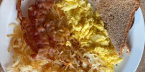Close-up shot of a plate with eggs, bacon, hashbrowns and toast.