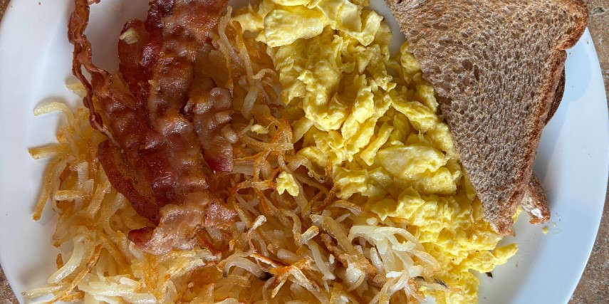 Close-up shot of a plate with eggs, bacon, hashbrowns and toast. 
