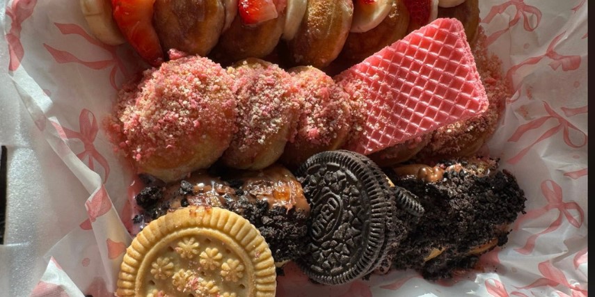 Close-up image of cookies and other sweets in a box lined with wax paper.