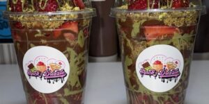 Two cups labeled with "Stacks and Drizzle" and filled with strawberries and drizzled with Dubai chocolate flavors.