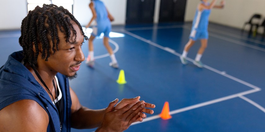 Close-up of a coach watching a group of female basketball players run drills.