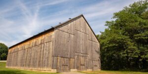 A historic tobacco barn against a blue sky streaked with clouds in Weston Bend State Park.