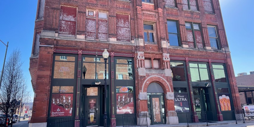 An older, large, multi-story brick building, viewed from the street.