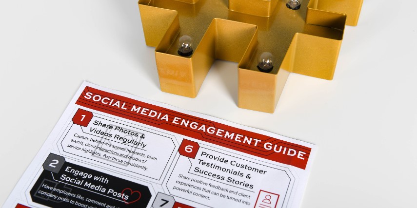 SJC's social media engagement guide on a table near a gold, lighted hashtag sign.