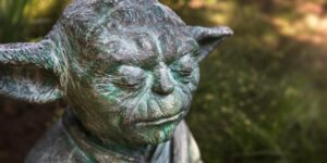 Stone sculpture of Yoda looking as if he is contemplating something.