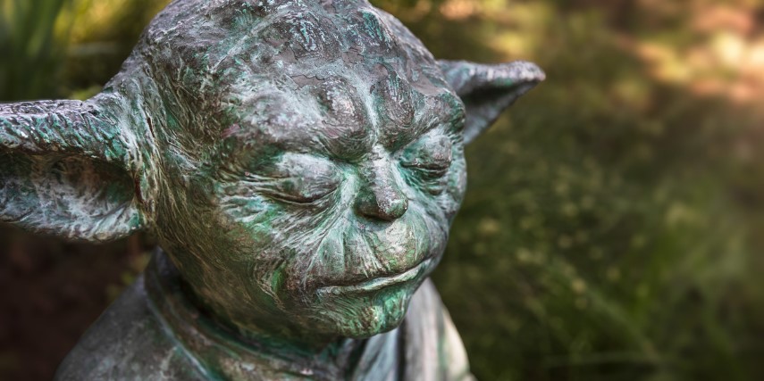 Stone sculpture of Yoda looking as if he is contemplating something.