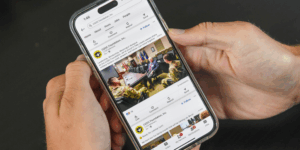 Close-up of a pair of hands holding a smartphone with a social media platform on the screen.